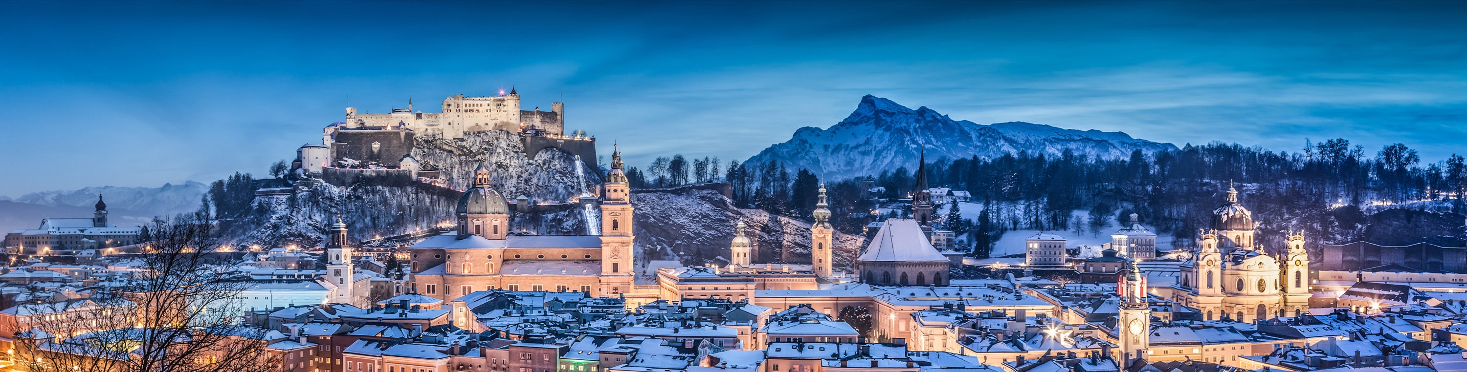 Salzburg bei Nacht im Winter, im Hintergrund Festungsbahn und Festung Hohensalzburg.